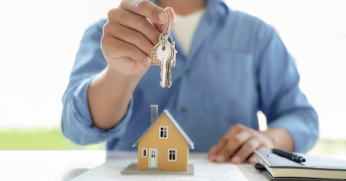Man übergibt Schlüssel zum eigenen Haus nach Kauf - Notarkosten - kleines Haus